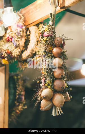 Corona appesa e treccia di cipolla su travi di legno, Zibelemärit tradizionale, mercato della cipolla a Berna, Svizzera, primo piano, cipolle commestibili (Allium cepa). Foto Stock