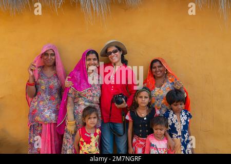 Jaisalmer, Rajasthan, India - 15th ottobre 2019 : Female viaggiatore e fotografo donna in posa con sorridente e felice Rajasthani donne e bambini Foto Stock