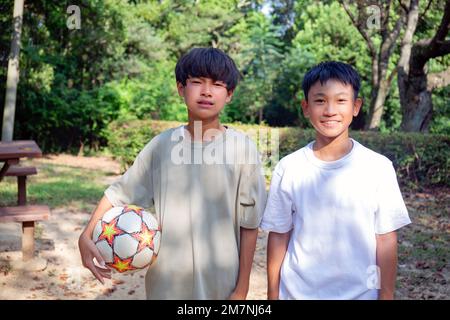 Due ragazzi di 13 anni in un parco con un calcio in estate. Foto Stock