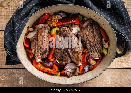 Stinco di agnello cotto a fuoco lento arrosto con verdure ed erbe aromatiche. Sfondo di legno. Vista dall'alto Foto Stock