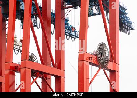 Un trasportatore rosso nel porto di Amburgo attende una nave container. Foto Stock