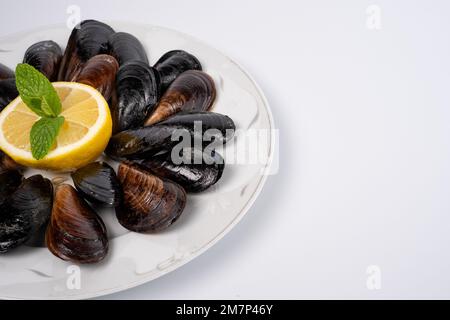 Top View Turkish Street Food stuffed cozze e limone su piatto isolato sfondo bianco. Crostacei neri per striscioni, cataloghi o menu. Foto Stock