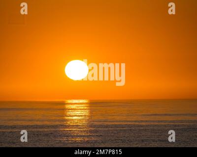 Il sole sta per passare in un cielo arancione vuoto appena sopra l'orizzonte sul Golfo del Messico Foto Stock