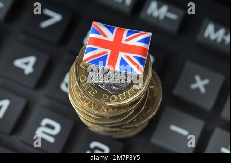 MONETE BRITANNICHE DA UNA LIBBRA CON LA BANDIERA DELL'UNIONE SUL CALCOLATORE RE COSTO DELLA CRISI VIVENTE L'INFLAZIONE DI ECONOMIA ECC UK Foto Stock