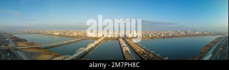 Vista panoramica dei ponti che attraversano l'ampio fiume fino alla distesa città al mattino presto Foto Stock