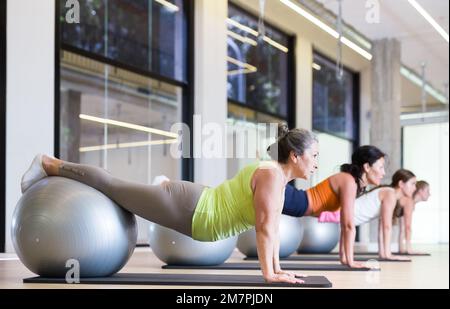 Maturo femmina esecuzione serie di esercizi con pilates palla Foto Stock