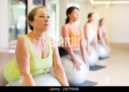 Maturo femmina esecuzione serie di esercizi con pilates palla Foto Stock