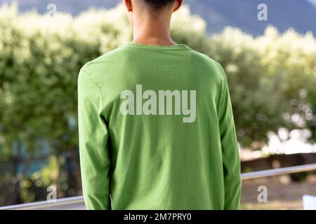 Immagine dell'uomo biraciale in verde lungo cimino con copyspace sopra gli alberi sullo sfondo Foto Stock