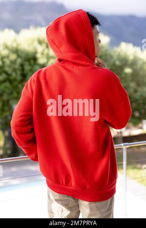 Immagine di un uomo biraciale con cappuccio rosso con copyspace sopra gli alberi sullo sfondo Foto Stock