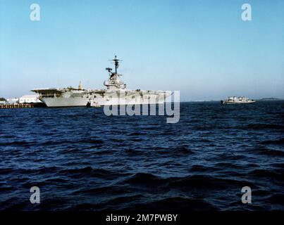 Vista del quarto porto della nave di addestramento di atterraggio dell'aeromobile ausiliario USS LEXINGTON (AVT 16) ormeggiata alla stazione aerea. Due rimorchiatori sono in primo piano. Base: Naval Air Station, Pensacola Stato: Florida (FL) Paese: Stati Uniti d'America (USA) Foto Stock