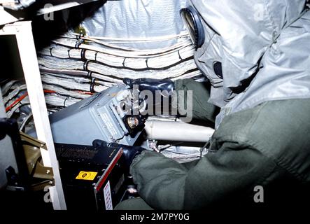 Vestito con attrezzatura da guerra chimica, un membro dell'equipaggio del 436th Avionics Maintenance Squadron, rimuove la scatola di controllo interfono del pilota R&R dall'abitacolo di un velivolo C-5A Galaxy durante un test delle attrezzature per la difesa da guerra chimica. Base: Dover Air Force base Stato: Delaware (DE) Paese: Stati Uniti d'America (USA) Foto Stock