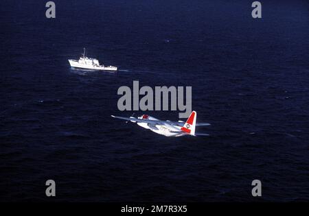 Vista di un aereo della Guardia Costiera HC-130 Hercules che pattuglia una zona di pesca. Una barca da pesca è sullo sfondo. Ingresso al concorso FOTOGRAFICO AAV, colore, marzo 1981. Paese: Oceano Pacifico (POC) Foto Stock