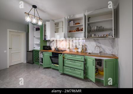 Le porte si aprono e i cassetti si aprono su nuovi mobili da cucina verdi e bianchi Foto Stock