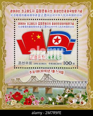 Foglio commemorativo nordcoreano del 2019 che celebra la visita di Kim Jong un in Cina, con bandiere nazionali e il Ponte dell'amicizia sino-coreana. Foto Stock