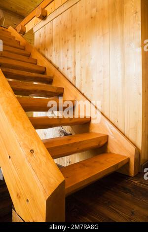 Scale in legno che conducono al piano superiore all'interno della casa di legno di cedro rosso artigianale. Foto Stock