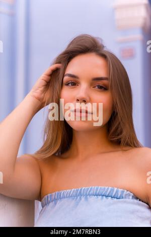 Stile di vita estivo, ritratto di bella giovane bionda donna in salopette blu sorridente Foto Stock