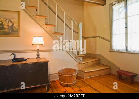 Vecchio tavolino in legno dipinto blu e scala nel soggiorno all'interno di una vecchia casa in legno in stile cottage del 1850 ricostruita. Foto Stock