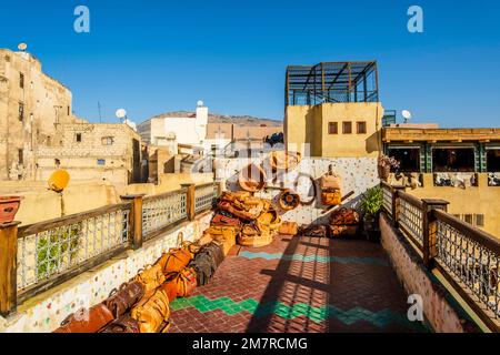Varietà di borse e pouffe in pelle esposti per la vendita su una terrazza con una vista conceria a Fes, Marocco, Nord Africa Foto Stock