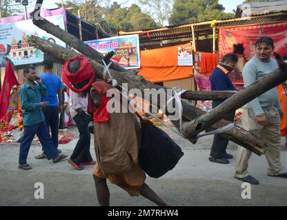 Kolkata, India. 11th Jan, 2023. Un pellegrino con disabilità che porta legno sulla spalla camminando verso la tenda sul Gangasgara transita nel campo di Kolkata. (Foto di Sudipta Das/Pacific Press) Credit: Pacific Press Media Production Corp./Alamy Live News Foto Stock