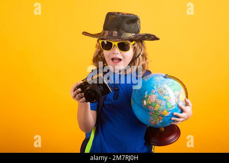 I turisti bambini con zaini e macchina fotografica tengono il mondo isolato su sfondo giallo. Avventura, viaggi e turismo concetto. Little explorer attivo Foto Stock