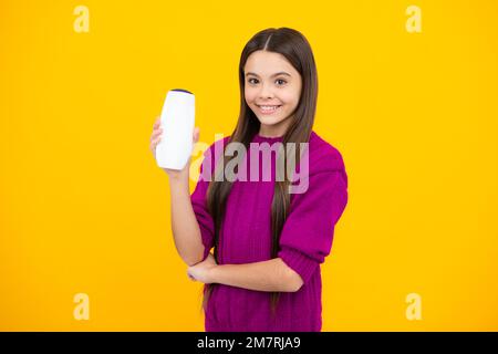 Ragazza adolescente con shampoo balsamo o gel doccia. Cura dei capelli dei bambini. Prodotto cosmetico per capelli, bottiglia di shampoo. Foto Stock