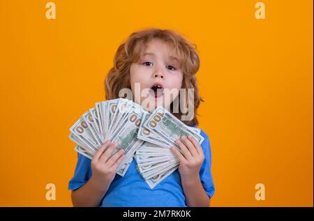 Capretto che mostra le fatture del dollaro dei soldi, levante in piedi sognante dei ricchi contro lo sfondo isolato dello studio. Foto Stock