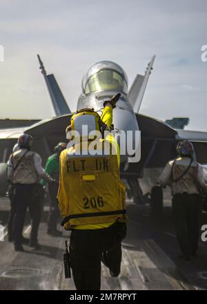 Mare delle Filippine, acque internazionali. 10th Jan, 2023. Mare delle Filippine, acque internazionali. 10 gennaio 2023. NEGLI STATI UNITI Il direttore del ponte di volo della Marina segnala a un aereo da combattimento F/A-18E Super Hornet, da tenere in taxi sul ponte di volo della portaerei di classe Nimitz USS Nimitz, 10 gennaio 2023 operante nel Mare delle Filippine. Credit: MC3 Joseph Calabrese/US Navy/Alamy Live News Foto Stock