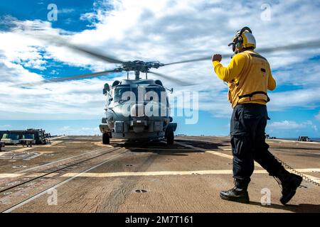 MARE DELLE FILIPPINE (12 maggio 2022) Boatswain’s Mate 2nd Class Jewlian Wilson, di Jacksonville, FLA, segnala un elicottero MH-60R Sea Hawk, assegnato ai “Raptors” di Helicopter Maritime Strike Squadron (HSM) 71, sul ponte di volo del cacciatorpediniere missilistico guidato di classe Arleigh Burke USS Spruance (DDG 111). Abraham Lincoln Strike Group è in fase di implementazione pianificata nell'area delle operazioni della flotta 7th degli Stati Uniti per migliorare l'interoperabilità attraverso alleanze e partnership e al tempo stesso fungere da forza di risposta pronta a sostegno di una regione indomPacifico libera e aperta. Foto Stock