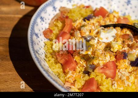 Piatto profondo su un tavolo di legno con pollo, riso e insalata di pomodoro grattugiati in casa. Concetto di cibo sano, naturale e fresco. Vista ravvicinata, Foto Stock