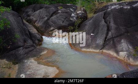 Acque calme del fiume, con formazioni rocciose nere e di montagna Foto Stock