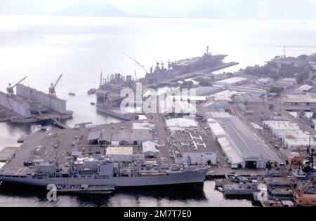 Una vista aerea del porto con le navi ormeggiate, compresa la portaerei USS KITTY HAWK (CV-63), in alto a destra, con il cacciatorpediniere USS INGERSOLL (DD-990) e i lubrificatori USNS NAVASOTA (T-AO-106) e USNS MISPILLION (T-AO-105) ormeggiate a poppa. La nave da combattimento USS SAN JOSE (AFS-7) è in basso a sinistra con la fregata USS HAROLD E. HOLT (FF-1074), il cacciatorpediniere USS o'BRIEN (DD-995) e il cacciatorpediniere missilistico guidato USS BUCHANAN (DDG-14) ormeggiato a prua. Base: Naval Station, Subic Bay Stato: Luzon Paese: Filippine (PHL) Foto Stock