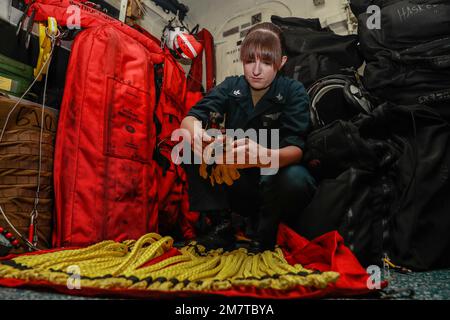 MARE DELLE FILIPPINE (12 maggio 2022) Aircrew Survival Equipmentman Classe 2nd Autunno Ybright, di Louisville, Ky., assegnato ai “Chargers” di Helicopter Sea Combat Squadron (HSC) 14, ispeziona le attrezzature di ricerca e salvataggio a bordo della portaerei di classe Nimitz USS Abraham Lincoln (CVN 72). Abraham Lincoln Strike Group è in fase di implementazione pianificata nell'area delle operazioni della flotta 7th degli Stati Uniti per migliorare l'interoperabilità attraverso alleanze e partnership e al tempo stesso fungere da forza di risposta pronta a sostegno di una regione indomPacifico libera e aperta. Foto Stock