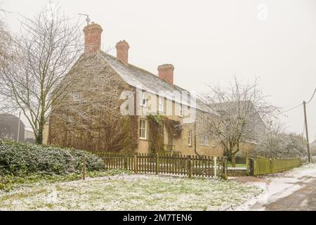 Una grande casa in pietra circondata da recinzione in legno in inverno Foto Stock