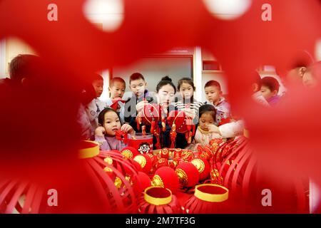 LIANYUNGANG, CINA - 11 GENNAIO 2023 - un insegnante guida i bambini a fare le lanterne in un asilo nido a Lianyungang, la provincia di Jiangsu della Cina orientale, Ja Foto Stock