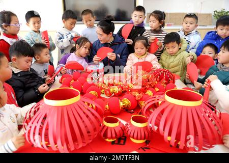 LIANYUNGANG, CINA - 11 GENNAIO 2023 - un insegnante guida i bambini a fare le lanterne in un asilo nido a Lianyungang, la provincia di Jiangsu della Cina orientale, Ja Foto Stock