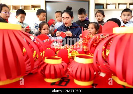 LIANYUNGANG, CINA - 11 GENNAIO 2023 - un insegnante guida i bambini a fare le lanterne in un asilo nido a Lianyungang, la provincia di Jiangsu della Cina orientale, Ja Foto Stock