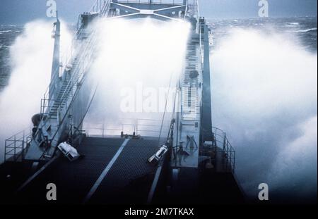 Un'onda si rompe sulla prua della nave cisterna USS RACINE (LST-1191) durante una tempesta in mare. Il RACINE fornisce servizio di scorta al missile pattuglia combattente (aliscafi) USS GEMINI (PHM-6) e USS HERCULES (PHM-2), in rotta verso il loro nuovo porto di casa a Key West, Flah. Paese: Oceano Pacifico (POC) Foto Stock