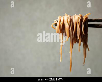 Primo piano di tagliatelle sulle bacchette Foto Stock