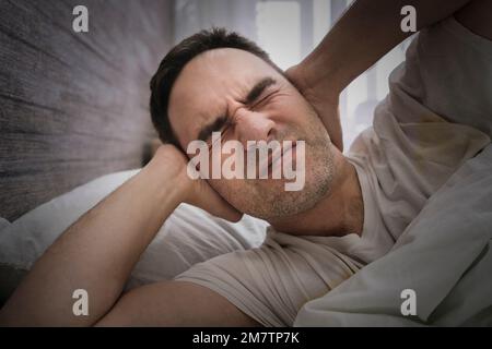 marito infastidito che blocca le orecchie dal rumore della moglie che russava in camera da letto. i vicini rumorosi interferiscono con il sonno. mal di testa Foto Stock