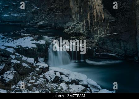 Una lunga esposizione di cascata parzialmente congelata di Aharbal durante una fredda giornata nuvolosa a Kulgam. Le acque del fiume Veshu, creano una delle cascate più maestose conosciute come le cascate di Aharbal o Niagara del Kashmir. Le cascate hanno un ambiente panoramico composto da fitte foreste di abeti, situato a sud di Srinagar. E' una delle migliori destinazioni turistiche nella Valle del Kashmir. Foto Stock