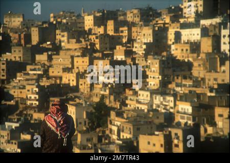 Aran wearing kaffiyeh looking at townhouses, Amman; Jordan Foto Stock