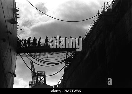 Una vista dei lavoratori che camminano attraverso la passerella mentre lasciano la corazzata NEW JERSEY (BB-62) per una pausa pranzo. Il NEW JERSEY è in dry dock dal novembre 1981, e viene rimontato e modernizzato per il ritorno al servizio attivo e la rimessa in servizio all'inizio del 1983. La rimessa in servizio sarà la quarta volta dalla costruzione della nave nel 1942. Base: Long Beach Naval Shipyard Stato: California (CA) Paese: Stati Uniti d'America (USA) Foto Stock