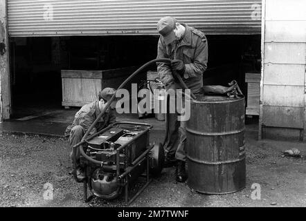 SSGT Clifford Hoffman, 164th Smoke Generator Detalment, regola una valvola del generatore di fumo M-3A3, mentre PFC Frank Robbins conduce i tubi flessibili in un barile da 4 galloni di olio per nebbia in preparazione all'avviamento dell'M-3A3 per una dimostrazione. Base: Fort Lewis Stato: Washington (WA) Nazione: Stati Uniti d'America (USA) Foto Stock