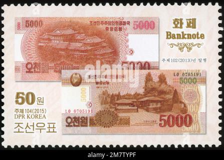 Francobollo nordcoreano del 2015 con banconote da 5000 won che mostrano il luogo di nascita di Kim il-sung e l'esposizione internazionale dell'amicizia. Foto Stock