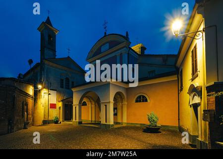 Due antiche chiese illuminate sulla piccola piazza acciottolata di Barolo, Piemonte, Italia settentrionale. Foto Stock