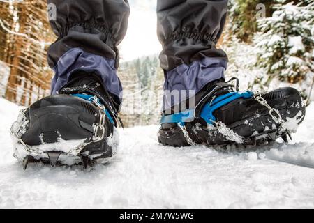 Ramponi sugli scarponi neri nella foresta innevata. Escursioni in inverno Foto Stock