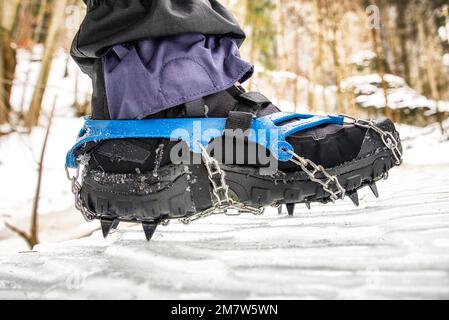 Ramponi sugli scarponi neri nella foresta innevata. Escursioni in inverno Foto Stock