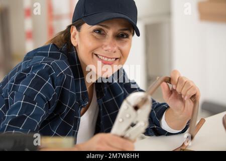 una donna felice che taglia tubi di rame Foto Stock