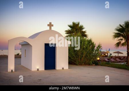 Faliraki, Grecia - 29 giugno 2022: Cielo colorato durante il tramonto sopra la cappella greca tradizionale sul mare della località Faliraki nell'isola di Rodi, Grecia Foto Stock