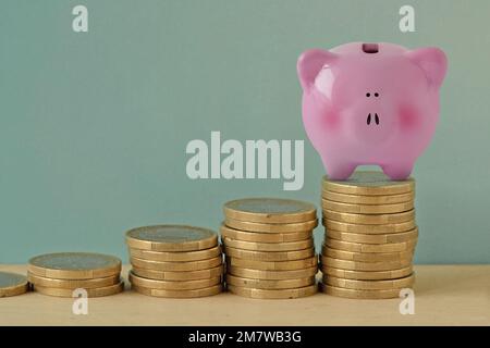 Piggy bank su raccogliere mucchi di monete - concetto di economia e risparmio di denaro Foto Stock